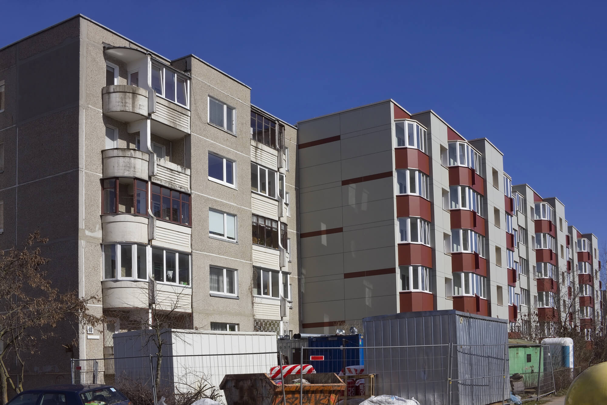 תמונת נושא של המאמר מה עדיף תמא 38 או פינוי בינוי המציגה שני בנייני דירות ישנים בהם מתבצעים שיפוצים ועל ידן עומדים פחי אשפה גדולים של בנייה.